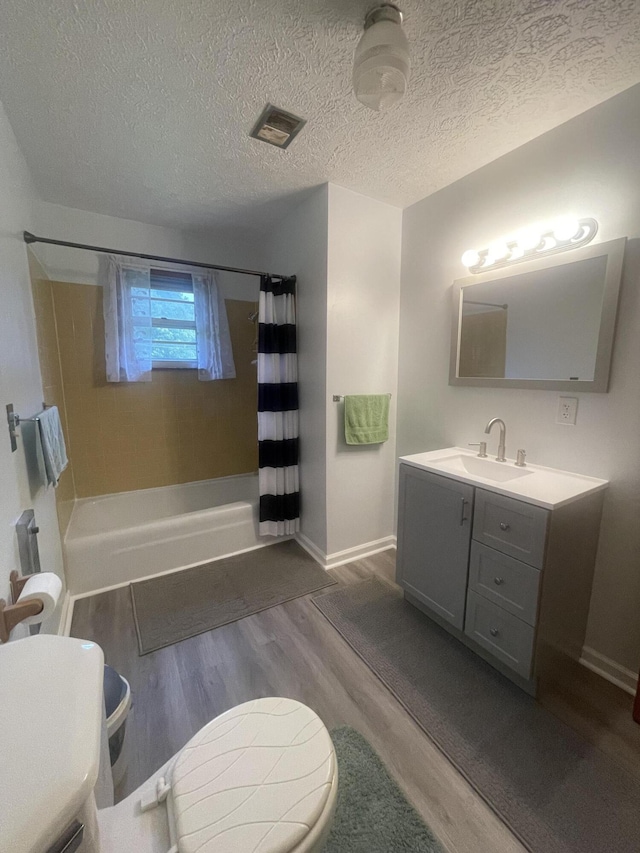 full bathroom with shower / tub combo, vanity, a textured ceiling, hardwood / wood-style flooring, and toilet