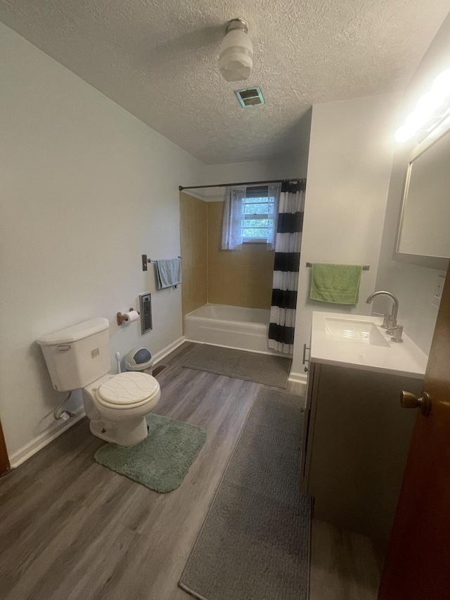 full bathroom featuring vanity, toilet, wood-type flooring, and a textured ceiling