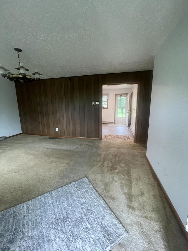 unfurnished room featuring light carpet, a textured ceiling, and wood walls