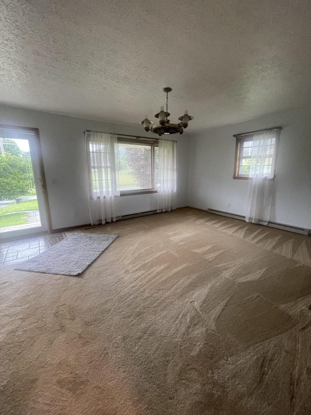 carpeted empty room with a textured ceiling and an inviting chandelier