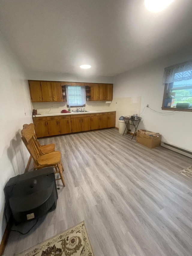 kitchen with baseboard heating, sink, and light hardwood / wood-style flooring