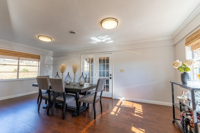 dining space featuring dark hardwood / wood-style flooring, crown molding, a wealth of natural light, and french doors