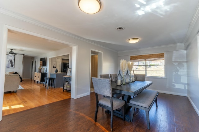 dining room featuring dark wood-type flooring, ceiling fan, and ornamental molding