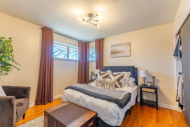 bedroom featuring hardwood / wood-style floors, a notable chandelier, and a textured ceiling