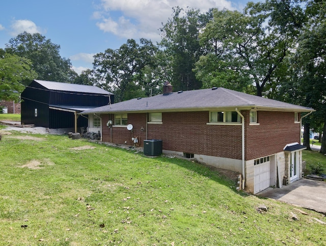 back of property with a garage, a lawn, and central air condition unit