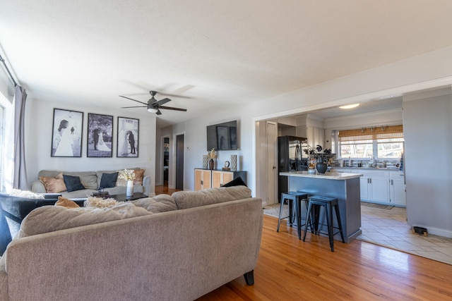 living room with sink, ceiling fan, and light hardwood / wood-style flooring