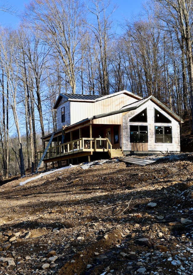 exterior space featuring covered porch, stone siding, and metal roof