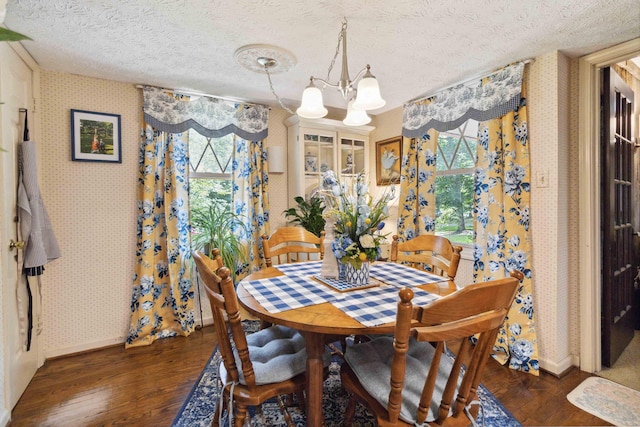 dining room with dark hardwood / wood-style flooring, a notable chandelier, and a textured ceiling