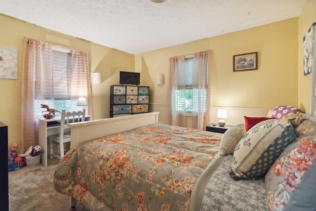 bedroom featuring multiple windows, carpet, and a textured ceiling