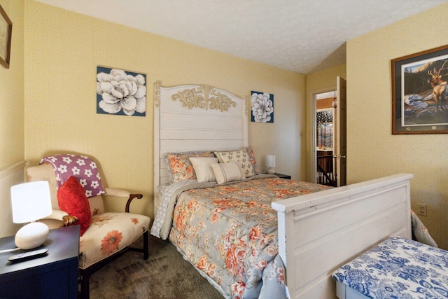 bedroom featuring a textured ceiling and dark colored carpet