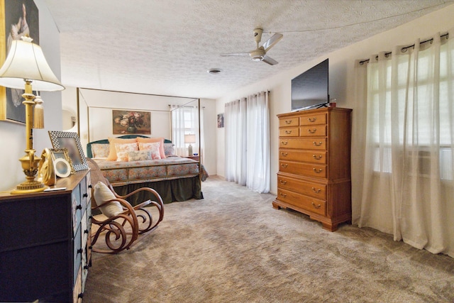 carpeted bedroom with ceiling fan and a textured ceiling