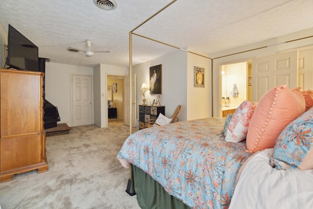 bedroom featuring ensuite bath, light colored carpet, and a textured ceiling