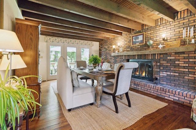 dining space featuring hardwood / wood-style flooring, a fireplace, beamed ceiling, and brick wall