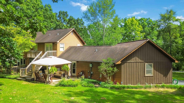 back of house with an outdoor living space, a patio, and a lawn