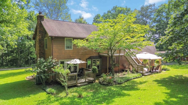 rear view of house featuring a wooden deck, a gazebo, and a lawn