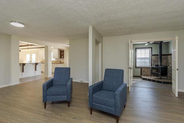 sitting room with wood-type flooring, a textured ceiling, and a wood stove