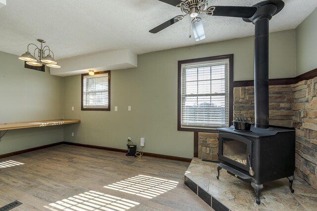 living room with plenty of natural light, light wood-type flooring, a textured ceiling, and a wood stove