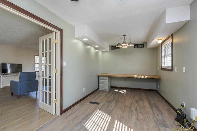 unfurnished office with a wealth of natural light, hardwood / wood-style floors, and a textured ceiling