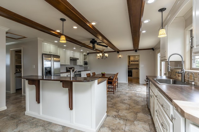 kitchen with sink, white cabinetry, a center island, hanging light fixtures, and stainless steel appliances