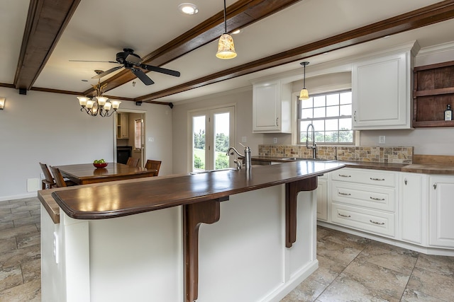 kitchen with ceiling fan, white cabinetry, butcher block counters, decorative light fixtures, and beamed ceiling