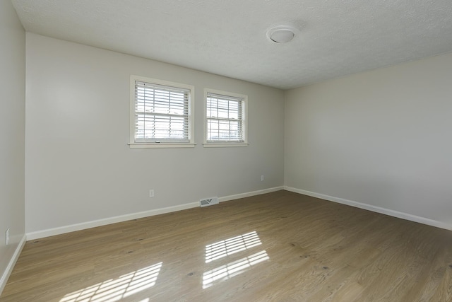 spare room with a textured ceiling and light wood-type flooring