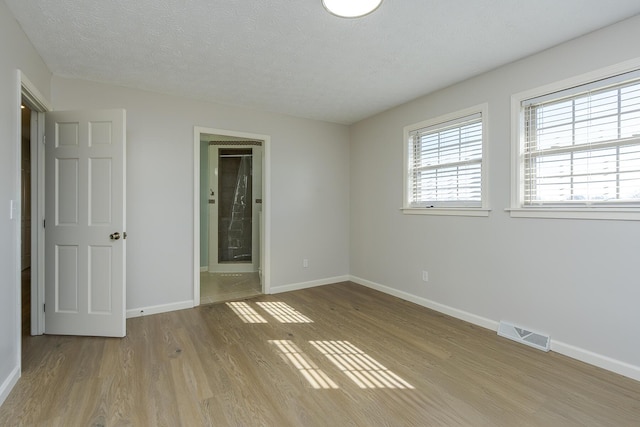 empty room with light hardwood / wood-style floors and a textured ceiling