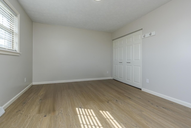 unfurnished bedroom with a closet, a textured ceiling, and light wood-type flooring