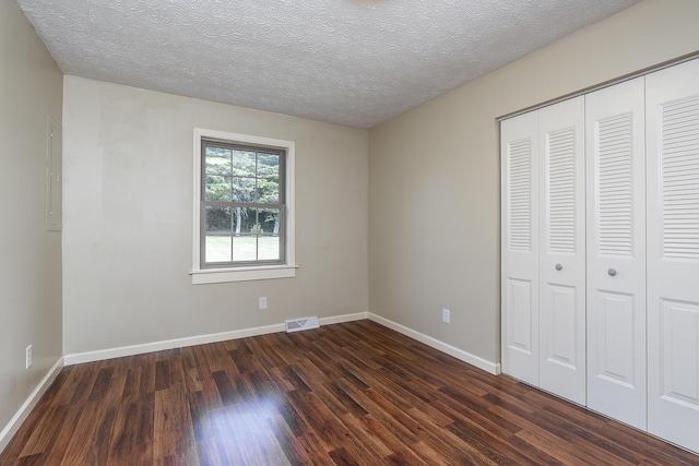 unfurnished bedroom featuring dark hardwood / wood-style flooring, a closet, and a textured ceiling