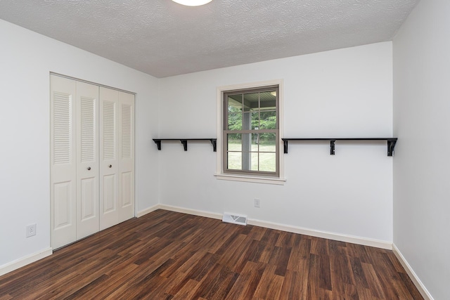 unfurnished bedroom featuring dark wood-type flooring, a closet, and a textured ceiling