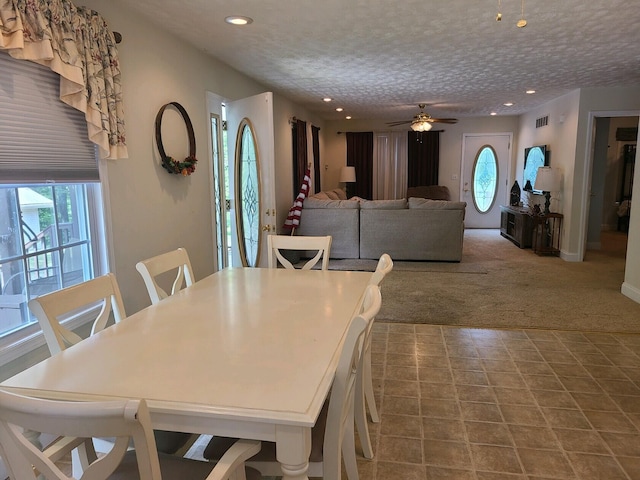 carpeted dining area featuring ceiling fan and a textured ceiling