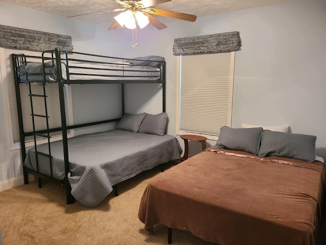 carpeted bedroom featuring ceiling fan and a textured ceiling