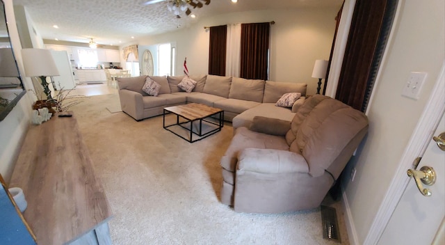 living room featuring ceiling fan and a textured ceiling