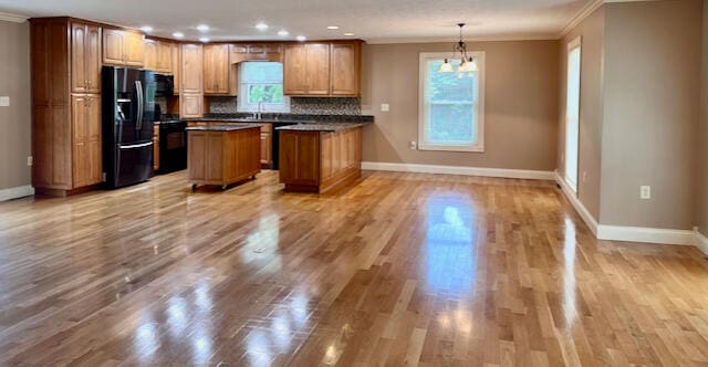 kitchen with black appliances, tasteful backsplash, ornamental molding, a center island, and light hardwood / wood-style floors