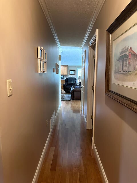 hallway featuring ornamental molding, hardwood / wood-style floors, and a textured ceiling