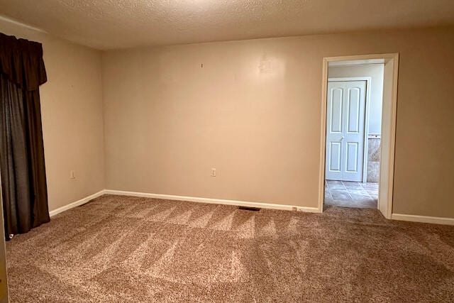 unfurnished room with carpet flooring and a textured ceiling