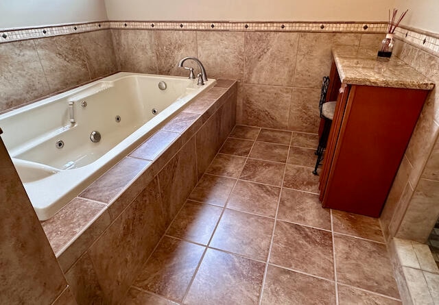 bathroom with a relaxing tiled tub, tile walls, and tile patterned floors