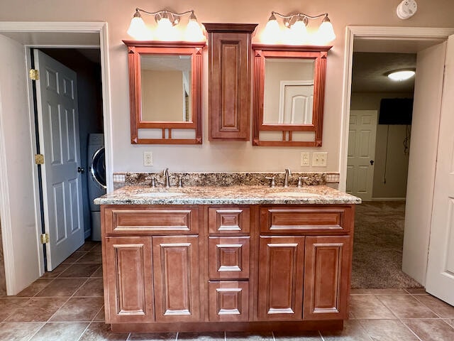 bathroom featuring dual vanity, washer / dryer, and tile patterned floors