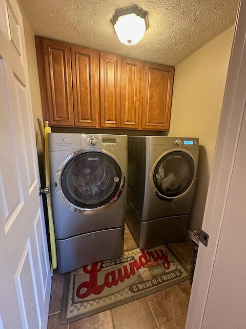 laundry area featuring tile patterned flooring, independent washer and dryer, cabinets, and a textured ceiling