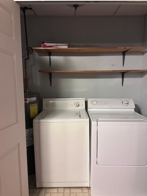 washroom with water heater, light tile patterned flooring, and washer and dryer