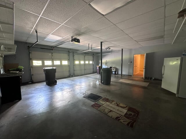 garage featuring white refrigerator and a garage door opener