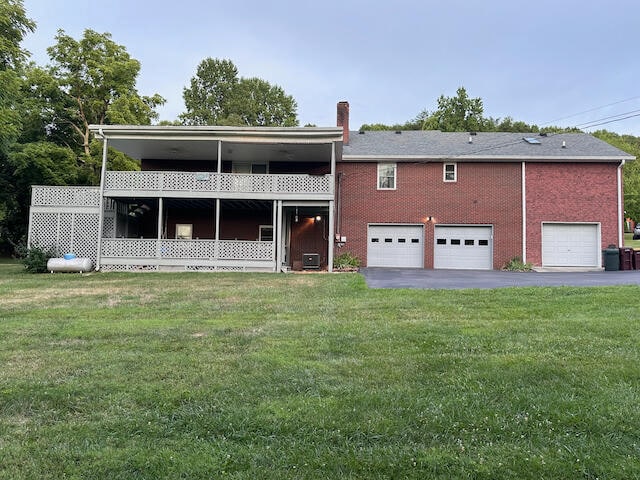 rear view of house featuring a garage and a yard