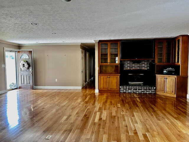 unfurnished living room featuring a fireplace, light hardwood / wood-style floors, and a textured ceiling