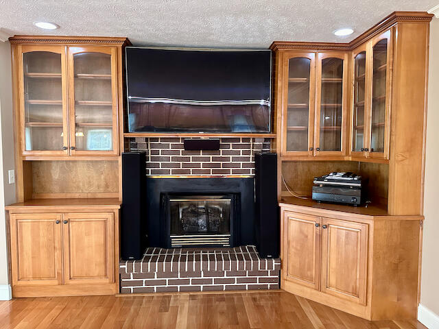 unfurnished living room with a textured ceiling, a fireplace, and hardwood / wood-style flooring