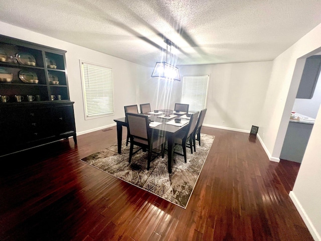 dining area featuring built in shelves, dark wood-type flooring, and a textured ceiling