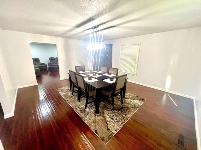 dining area with a textured ceiling and dark hardwood / wood-style floors