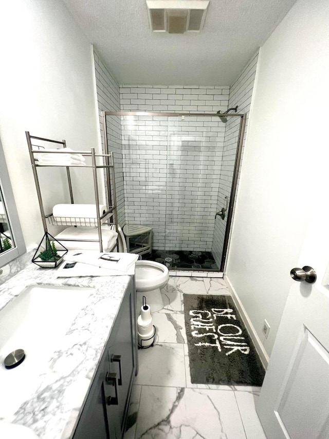 bathroom with vanity, toilet, a tile shower, and a textured ceiling