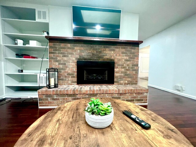 living room with a fireplace and dark wood-type flooring