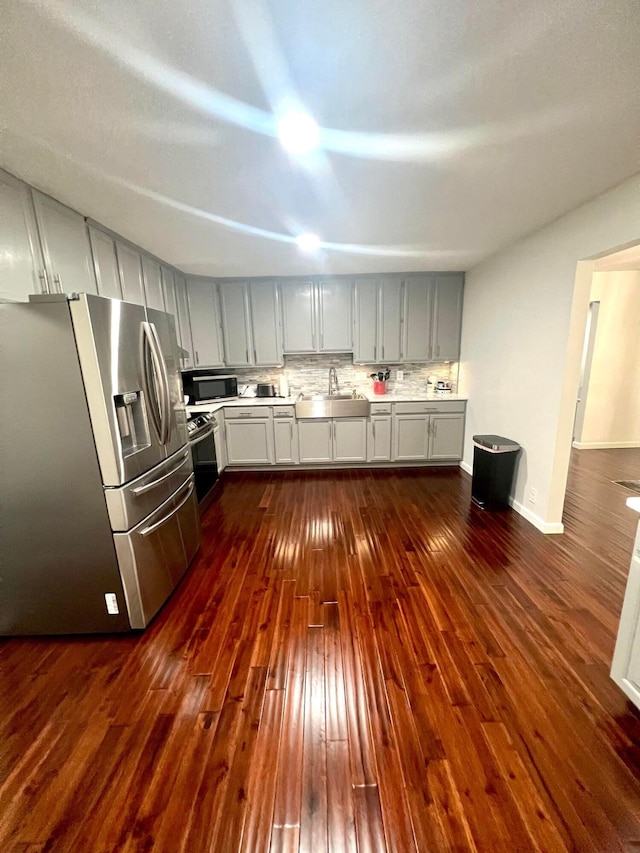 kitchen with tasteful backsplash, sink, stainless steel appliances, and dark hardwood / wood-style floors