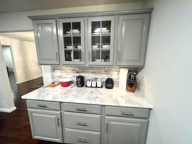 bar with decorative backsplash, gray cabinets, and light stone counters