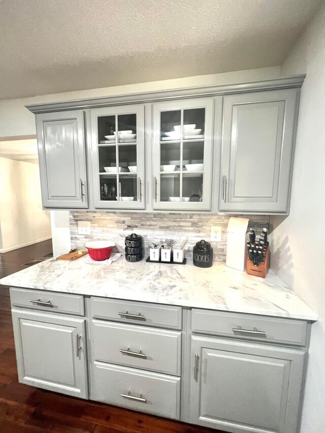 bar with backsplash, light stone counters, and gray cabinetry